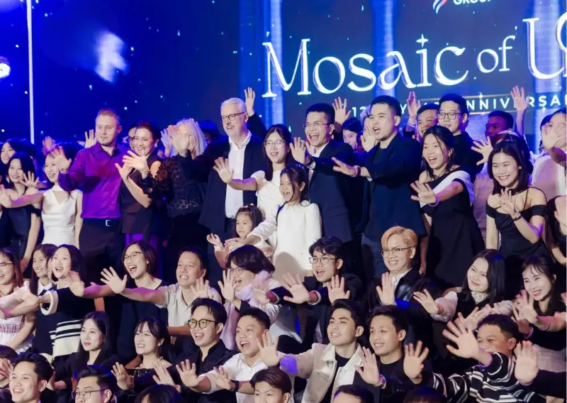 BSS team members and leaders raising their hands together on stage under a Mosaic of Unity anniversary backdrop