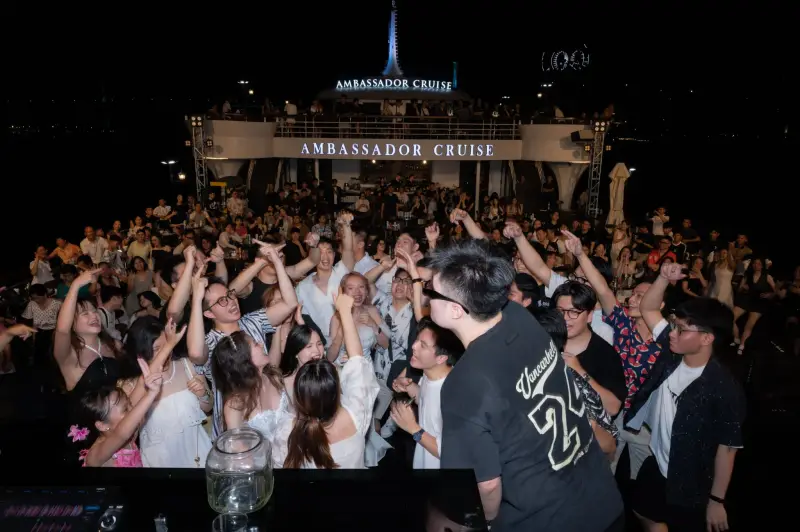 A crowd of BSS team members cheering at an evening event on a boat