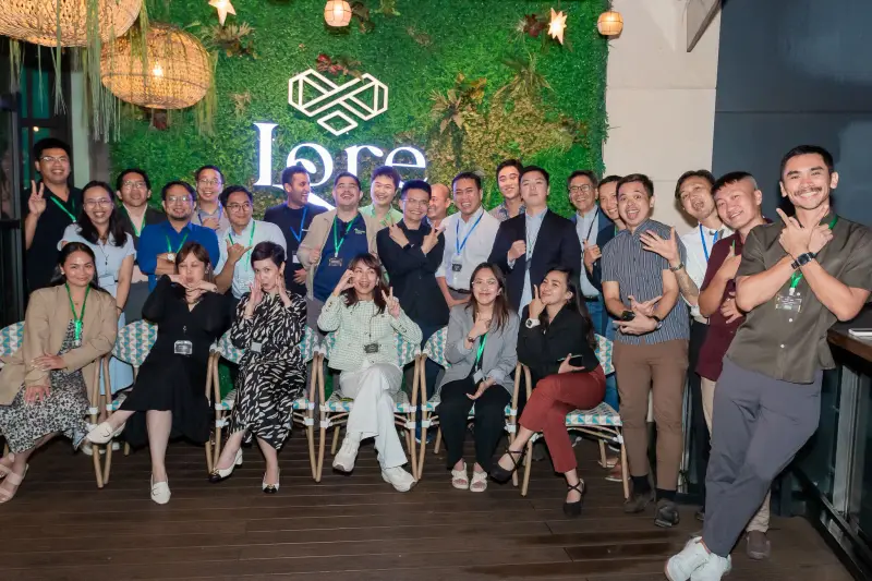 BSS team members posing together at an indoor gathering in front of a green plant wall