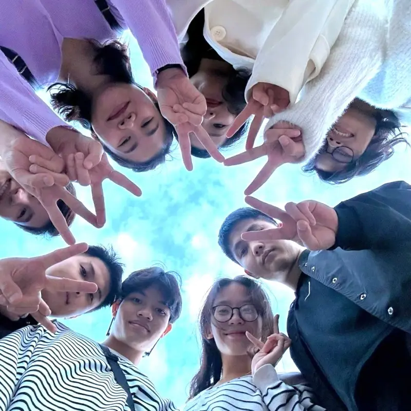 Smiling BSS team members making peace signs, photographed from below in a circle
