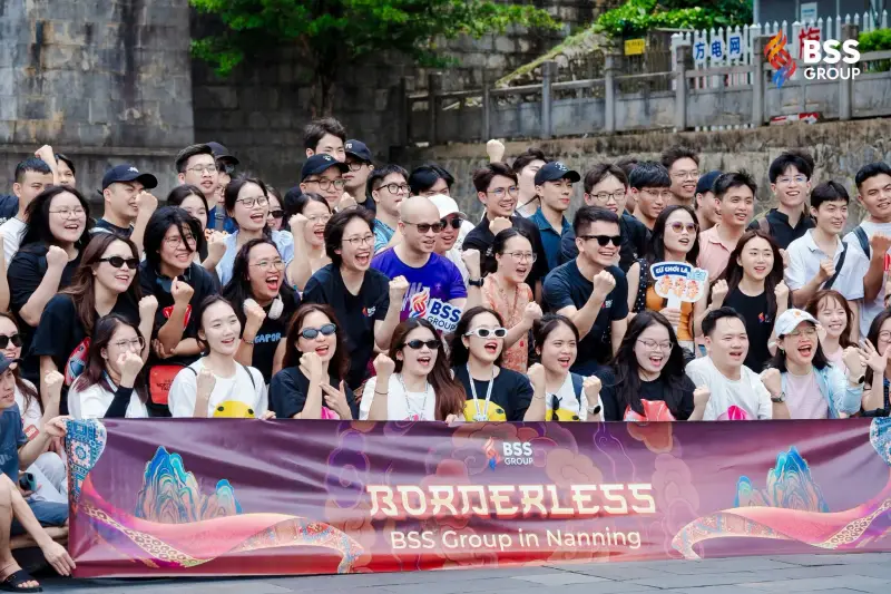 Cheering BSS team members crowded together behind a banner reading Borderless, BSS Group in Nanning
